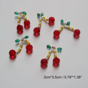 Può includere: Cinque paia di orecchini pendenti a forma di ciliegia rossa e verde con perline bianche e gialle. Ogni ciondolo misura circa 2 cm per 3,5 cm.