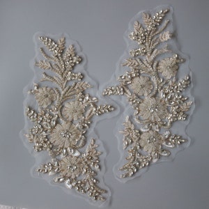 May include: Two gold and white beaded floral appliques with crystal embellishments on a sheer fabric background.