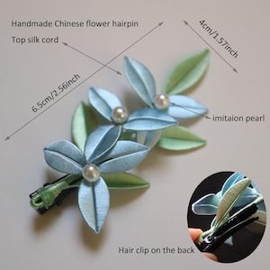 Puede incluir: Horquilla de flores china hecha a mano con flores de seda azul claro y verde y centros de perlas de imitaci&oacute;n. La horquilla mide 6,5 cm de largo y 4 cm de ancho, con una pinza para el pelo en la parte posterior.