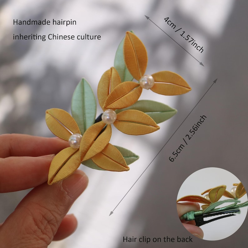Puede incluir: Una horquilla hecha a mano con un dise&ntilde;o floral, con hojas amarillas y verdes y perlas de imitaci&oacute;n. La horquilla mide 6,5 cm de largo y 4 cm de ancho. El texto de la imagen dice: "Horquilla hecha a mano que hereda la cultura china."