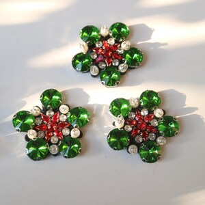 May include: Three green and red jeweled flower embellishments with white pearl accents.
