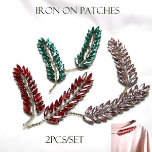 May include: A set of three iron-on patches featuring a leaf design. The leaves are made of rhinestones in red, green, and pink. The patches are labeled "2PCS/SET".