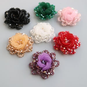 May include: Assortment of seven beaded flower embellishments in various colors, including black, green, pink, white, beige, red, and purple.