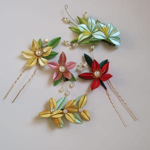 May include: Five handmade silk flower hair clips and pins. The clips and pins feature a variety of colors, including green, yellow, red, pink, and white. The flowers are decorated with small pearl beads.