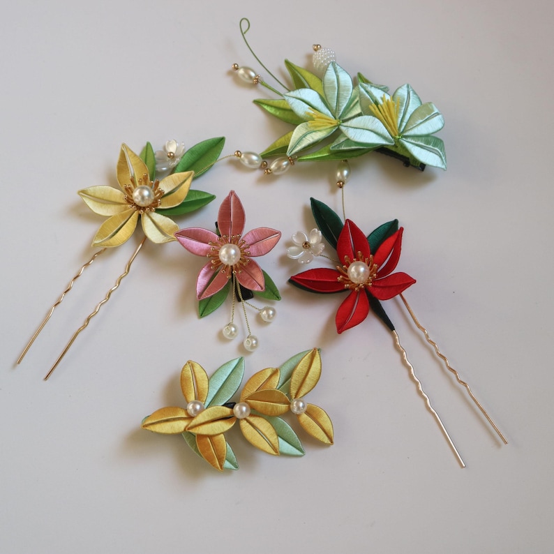 May include: Five handmade silk flower hair clips and pins. The clips and pins feature a variety of colors, including green, yellow, red, pink, and white. The flowers are decorated with small pearl beads.
