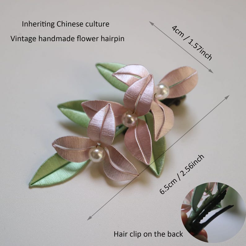 Puede incluir: Una horquilla de flores vintage hecha a mano. El accesorio para el cabello presenta flores de tela rosa con detalles de perlas y hojas verdes. La horquilla mide 6,5 cm de largo y 4 cm de ancho. El texto en la imagen dice: Inheriting Chinese culture, Vintage handmade flower hairpin.