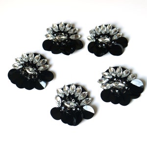 May include: Five black and silver round embellishments with rhinestones and sequins.