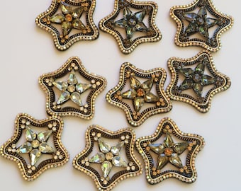 Puede incluir: Nueve adornos en forma de estrella con una variedad de colores y diseños de cristal. Los adornos están hechos de metal dorado y tienen una superficie texturizada en relieve.