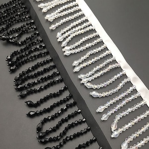 May include: Two rows of fringe trim, one black and one clear. The black fringe is made of small, round beads. The clear fringe is made of faceted beads.