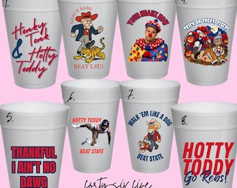 Puede incluir: Un juego de ocho vasos de espuma blancos con varios estampados gráficos que incluyen textos como Honky Tonk & Hotty Toddy, Geaux Rebs, Your Heaux Now, Trick or Treat Tigers, Thankful I Ain't No Dawg, Hotty Toddy Beat State y Walk 'Em Like A Dog.
