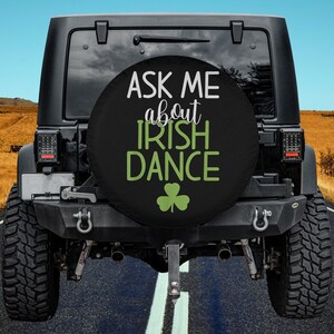 May include: Black spare tire cover with white text that reads "Ask me about Irish Dance" and a green shamrock.