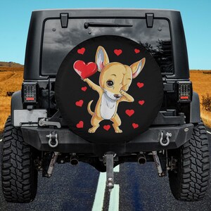 May include: A black spare tire cover with a cartoon chihuahua doing the dab dance and holding a red heart. The background is black with red hearts.
