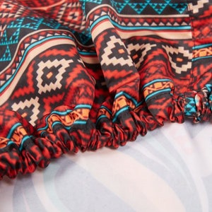 May include: Close-up of a red, black, and blue patterned fabric with a gathered edge. The fabric has a geometric design.