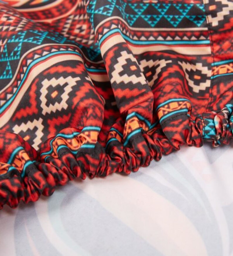 May include: Close-up of a red, black, and blue patterned fabric with a gathered edge. The fabric has a geometric design.