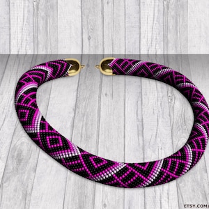 Può includere: Una collana di perline rosa, nera e bianca con un motivo geometrico. La collana è realizzata con perline a seme e ha una chiusura dorata.