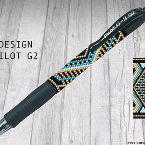 Op de afbeelding: Een zwarte Pilot G2 pen met een kralenontwerp in blauw, wit en goud. De pen ligt op een houten achtergrond. De tekst "PILOT G-2 07" is op de pen gedrukt. De tekst "BYADINDA Patterns" is gedrukt in de rechterbovenhoek van de afbeelding.