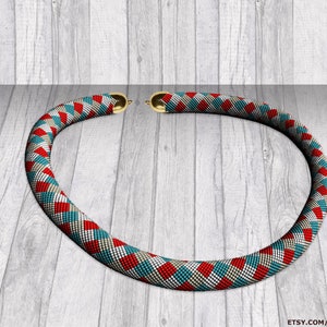Può includere: Una collana di perline rosse, bianche e blu con una chiusura dorata. La collana è realizzata con piccole perline quadrate e disposte in un motivo geometrico. La collana è appoggiata su una superficie di legno.