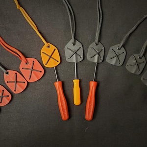 May include: Nine leather keychains with an X design in various colors, including black, orange, and blue. Three screwdrivers are also included.