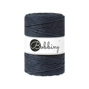 May include: A spool of dark blue cotton rope with the brand name "Bobbiny" printed on a white label.