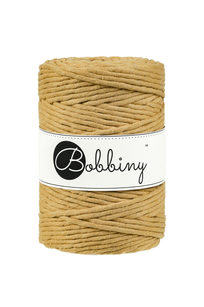 May include: A spool of tan cotton cord, wrapped in a white label with the text "Bobbiny&trade;".