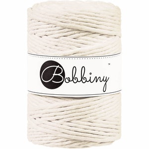 May include: A spool of off-white cotton rope with a white label that says "Bobbiny" in black cursive lettering.