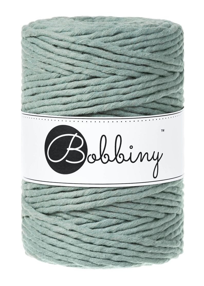 May include: A spool of light green cotton rope with the brand name "Bobbiny" printed on a white label.