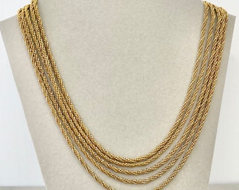 May include: A gold multi-strand necklace with a rope chain design. The necklace is layered with five strands of chain.