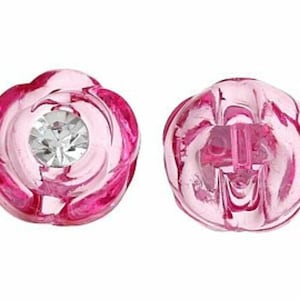 Puede incluir: Dos pendientes rosas con forma de flor, cada uno con una piedra central clara y brillante. Los pendientes tienen un aspecto translúcido y un diseño detallado de pétalos. Primer plano sobre fondo blanco.