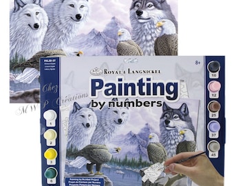 May include: A paint-by-numbers kit featuring a snowy mountain scene with three white wolves and two bald eagles. The kit includes a canvas, paints, and brushes. The box is labeled "Painting by numbers" and "Royal & Langnickel".