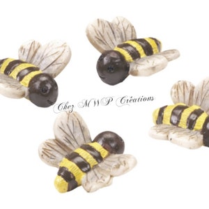 Può includere: Quattro piccole statuine di api in ceramica con strisce nere e gialle. Le api hanno ali bianche e teste marroni con occhi neri.