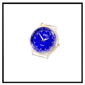 Può includere: Un orologio dorato con un quadrante blu e un cinturino in cristallo trasparente. Il quadrante presenta un motivo floreale bianco e il testo "CCC QUARTZ".