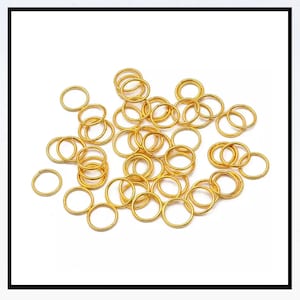 Peut inclure: Un tas de anneaux de jonction dorés, un type de composant de bijouterie utilisé pour relier les chaînes, les cordons et autres composants de bijoux.