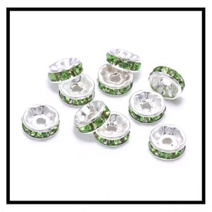 May include: Ten silver-toned bead caps with a row of light green rhinestones around the edge.