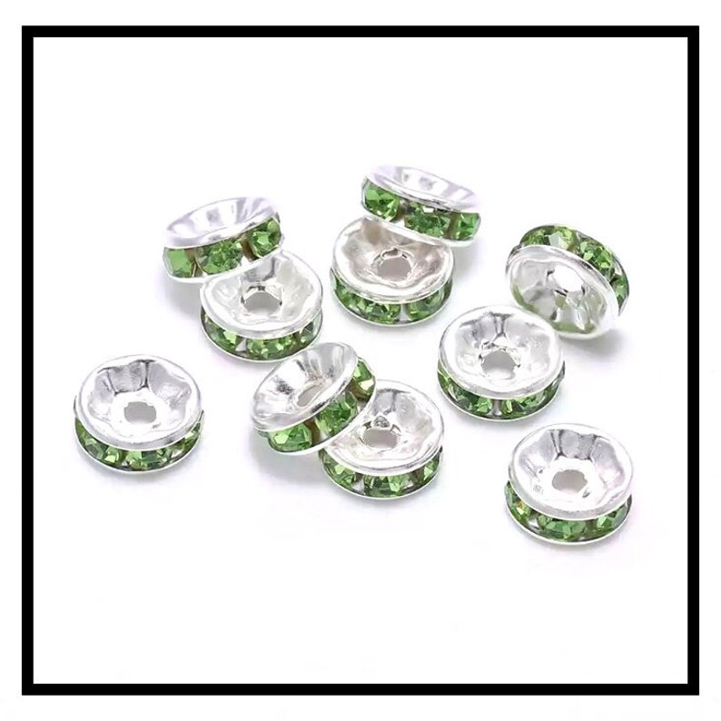 May include: Ten silver-toned bead caps with a row of light green rhinestones around the edge.