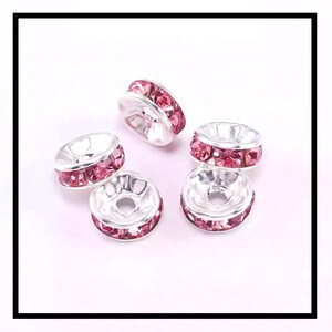 May include: Five silver-toned bead caps with a single row of pink rhinestones around the edge.