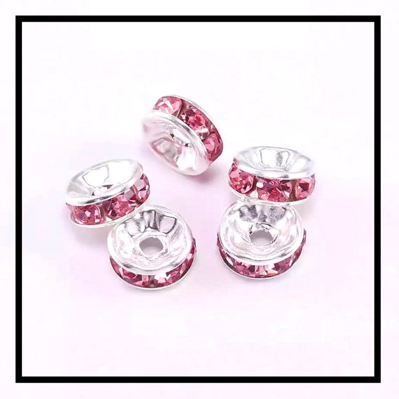 May include: Five silver-toned bead caps with a single row of pink rhinestones around the edge.