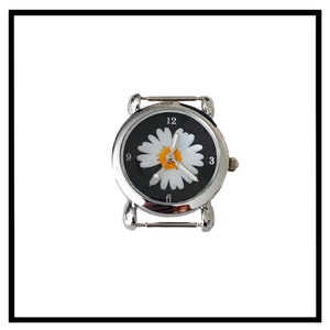 Può includere: Un orologio argentato con un quadrante nero e un design a margherita bianca. L'orologio ha un cinturino argentato e una chiusura.