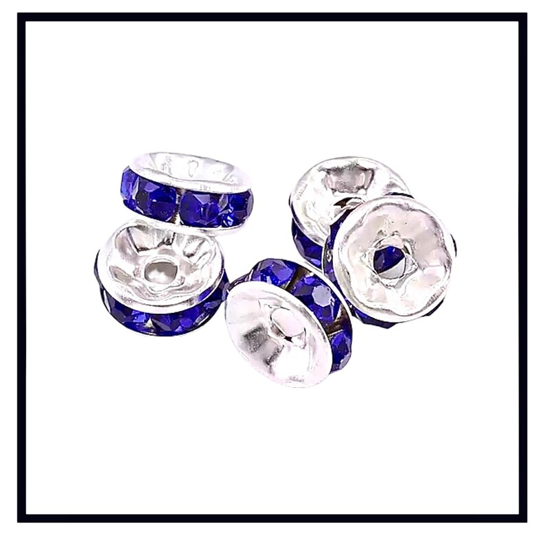 May include: A set of five silver-toned bead caps with a row of blue rhinestones around the edge. The caps are designed to be used as a decorative accent for jewelry making.