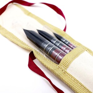 May include: A set of three black and red calligraphy brushes in a beige canvas case with a red ribbon.