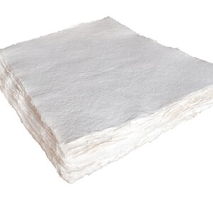 K&ouml;nnte beinhalten: Ein Stapel wei&szlig;er handgemachter Papierschichten mit einer rauen, strukturierten Oberfl&auml;che.