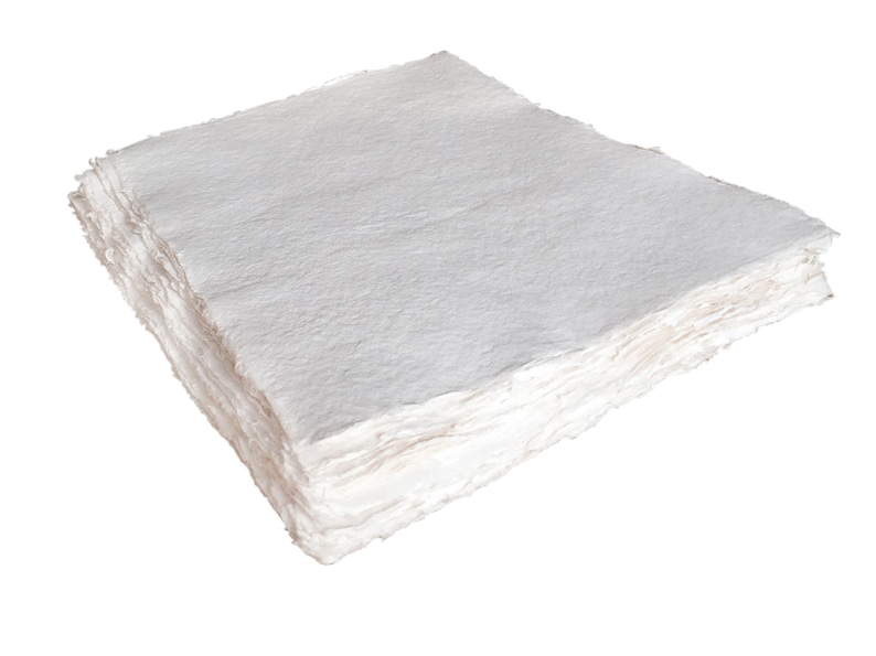 K&ouml;nnte beinhalten: Ein Stapel wei&szlig;er handgemachter Papierschichten mit einer rauen, strukturierten Oberfl&auml;che.