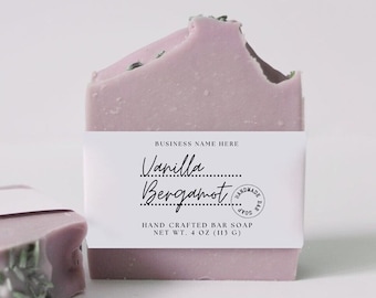 May include: A bar of handmade soap with a label that reads "Vanilla Bergamot" and "HAND CRAFTED BAR SOAP NET WT. 4 OZ (113 G)". The soap is a light purple color and has a speckled appearance.