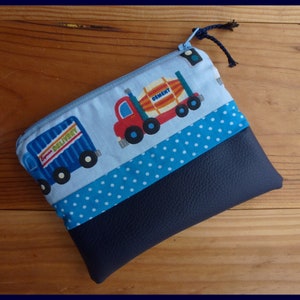 Peut inclure: Une pochette zippée bleue et marine avec un motif de camion et de bétonnière. La partie supérieure a un fond bleu clair avec des camions bleus et les mots "Express Delivery" et "Cement". Le bas est bleu marine.