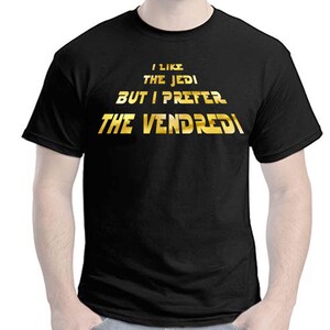 Peut inclure: T-shirt noir avec un texte doré qui dit "J'aime les Jedi mais je préfère le Vendredi."