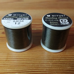 May include: Two spools of black beading thread, one labeled "MIYUKI Beading Thread 330dtex 100% NYLON Made in Japan LOT. BJO5R COL. 12" and the other labeled "MIYUKI Beading Thread ビーズステッチ糸 50m (55yds.) フィルム:PET"