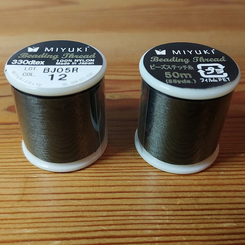 May include: Two spools of black beading thread, one labeled "MIYUKI Beading Thread 330dtex 100% NYLON Made in Japan LOT. BJO5R COL. 12" and the other labeled "MIYUKI Beading Thread ビーズステッチ糸 50m (55yds.) フィルム:PET"