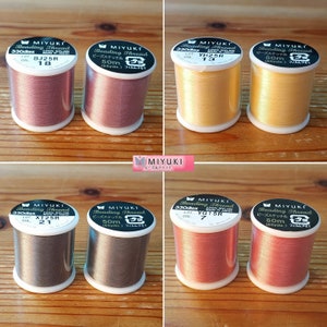 May include: Six spools of beading thread in various colors, including gold, pink, brown, and gray. Each spool is labeled with the brand name "MIYUKI" and the text "Beading Thread".
