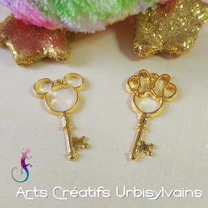 Peut inclure: Deux breloques clés de couleur dorée, l'une en forme de Mickey Mouse et l'autre en forme d'empreinte de patte. Les deux breloques ont un design de trou de serrure.