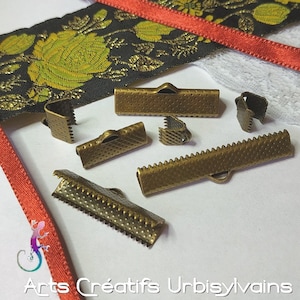 Op de afbeelding: Een set van acht antieke gouden metalen sluitingen voor lint of stof. De sluitingen hebben verschillende ontwerpen, waaronder een gegolfde rand, een gestippeld patroon en een eenvoudige lus.