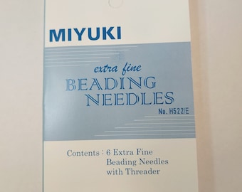 May include: A white package with blue text that reads "MIYUKI extra fine BEADING NEEDLES No. H522/E". The package also says "Contents: 6 Extra Fine Beading Needles with Threader" and "MADE IN JAPAN".